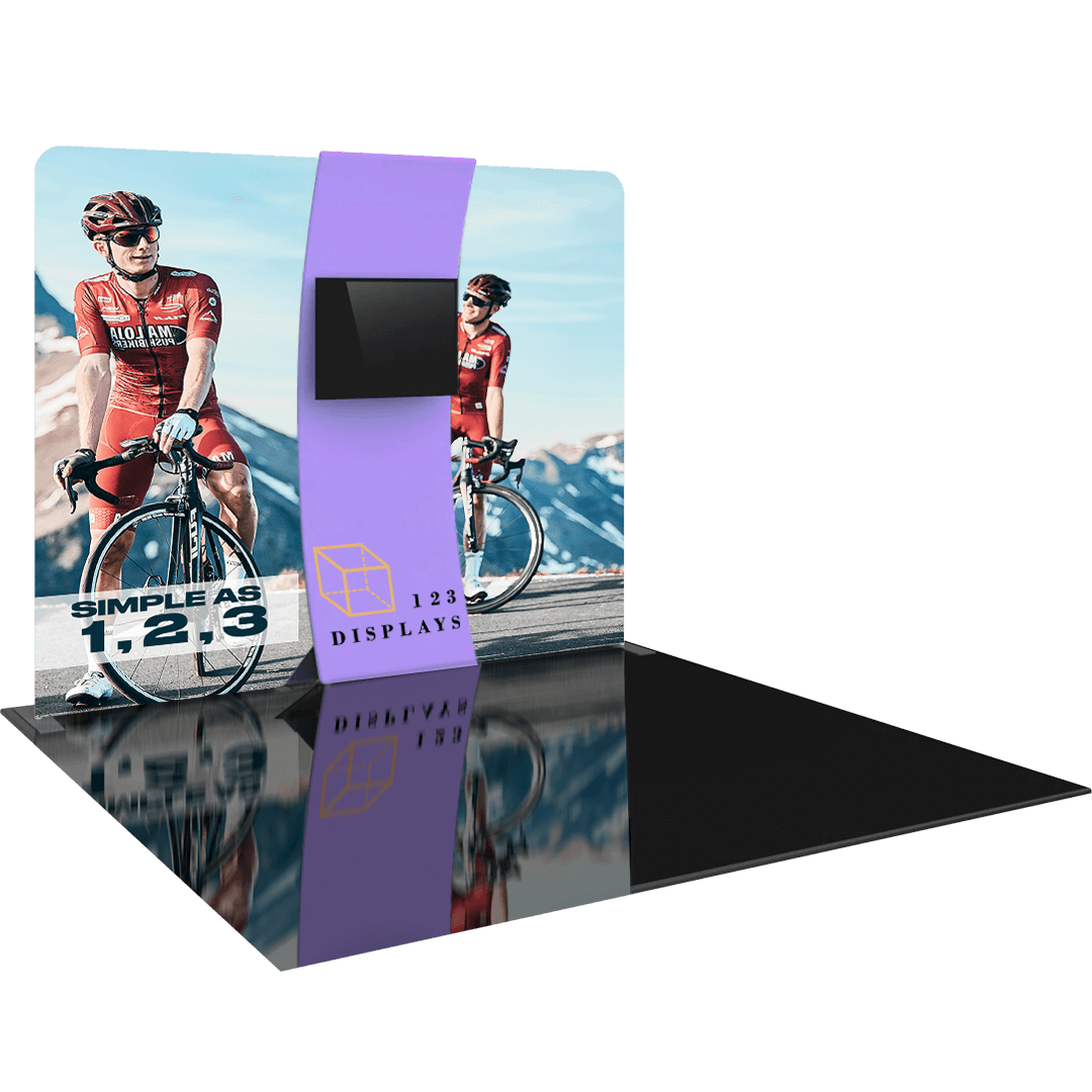 Two cyclists in red racing uniforms riding bikes near mountains, with a 3D rendering of a purple trade show display tower featuring the 123displays logo and "Simple as 1,2,3" slogan reflected on the glossy black floor surface.